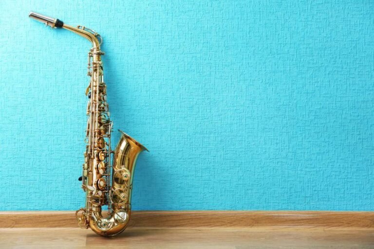 Alto saxophone placed against a turquoise wall – learn saxophone with easy lessons for beginners.