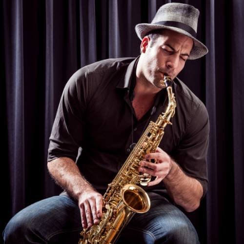 Saxophonist holding a gold alto saxophone during a private lesson in Dubai — promoting beginner saxophone classes.